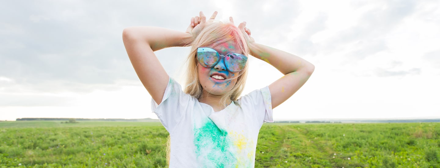 child in white t-shirt covered in colour powder