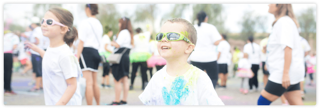A boy smiling at a colour run.
