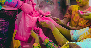 Adult distributing holi powder to a group of children