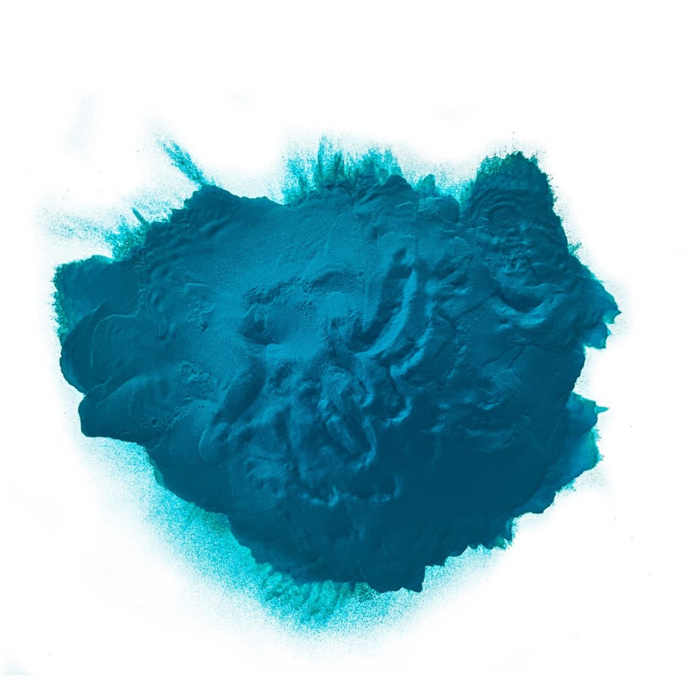A heap of turquoise colored powder against a white background.