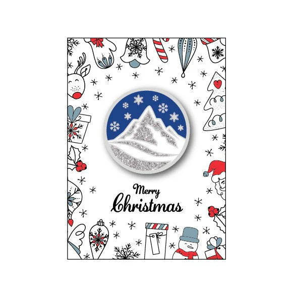 Christmas-themed badge with mountain design and festive illustrations on a white background.