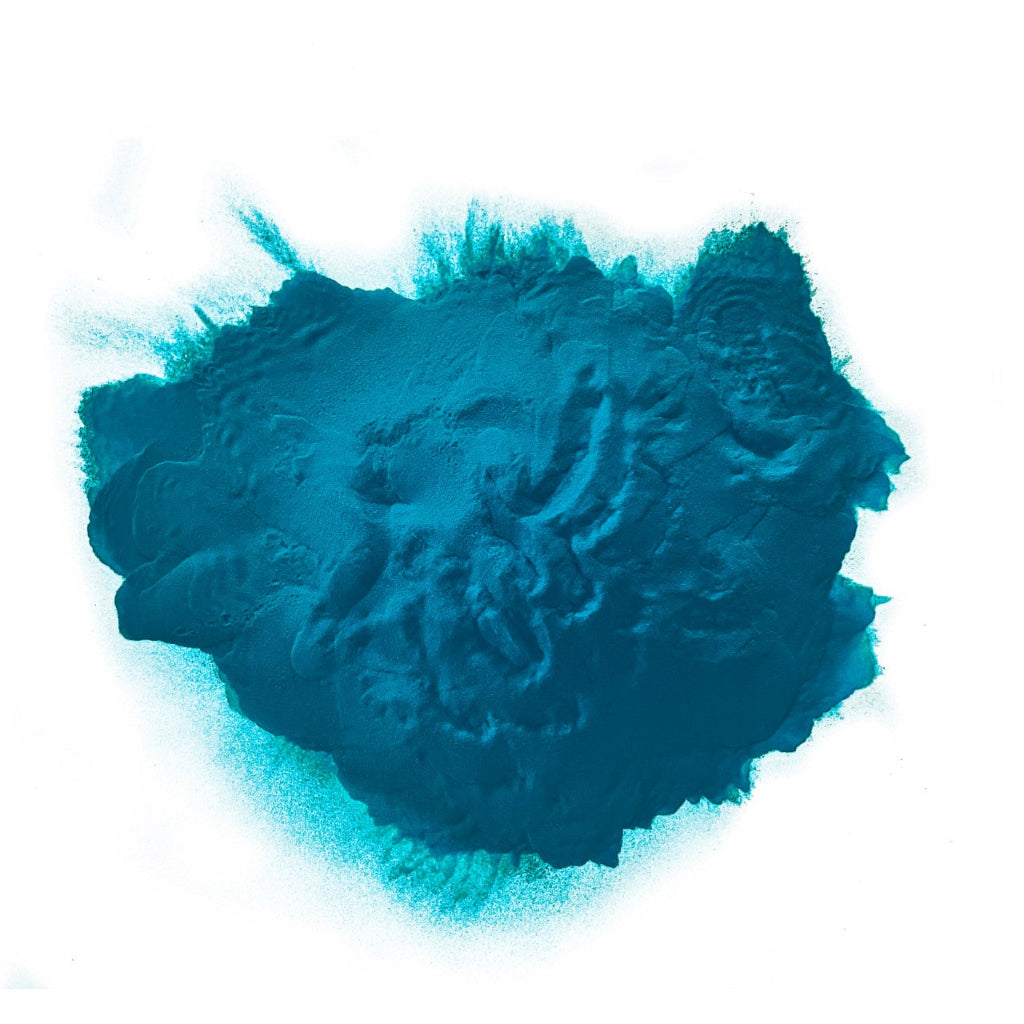 A heap of turquoise colored powder against a white background.