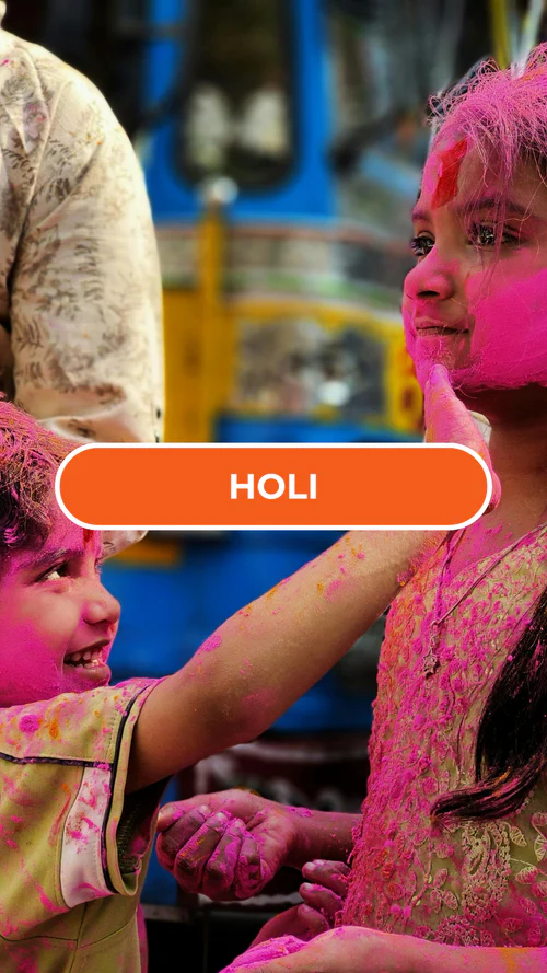 Two children joyfully celebrate Holi, their faces and clothes covered in vibrant pink powder. A girl playfully touches a boy's face, both smiling.