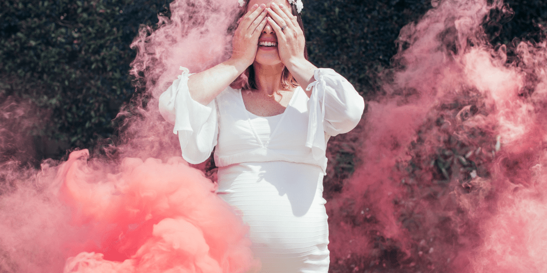 Person in a white dress standing amidst pink smoke