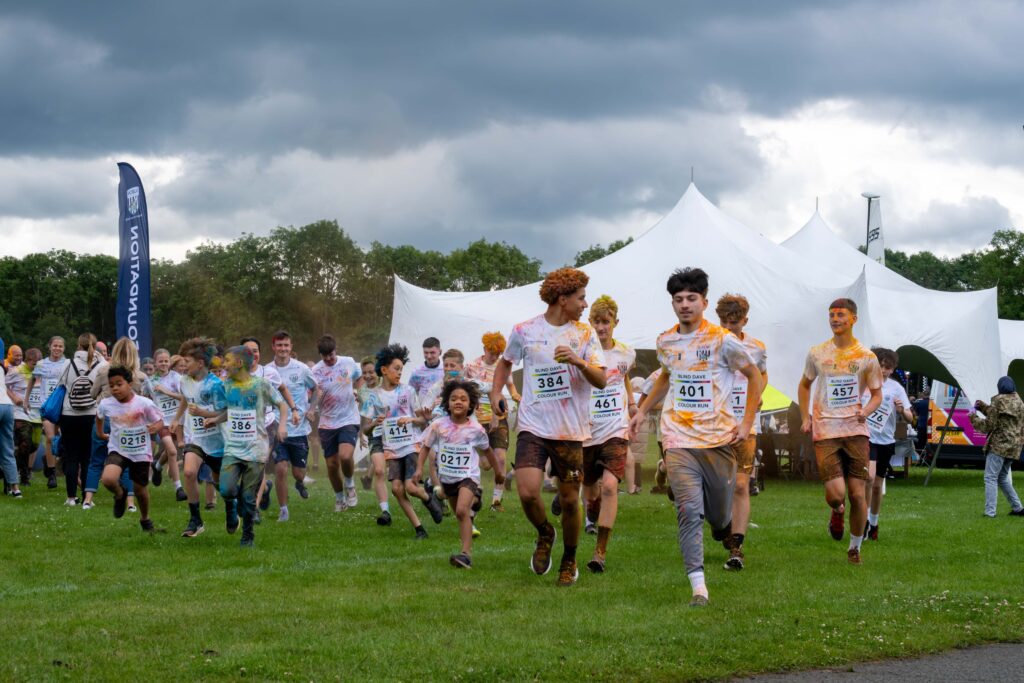 Children covered in vibrant colour powder, running in a race.