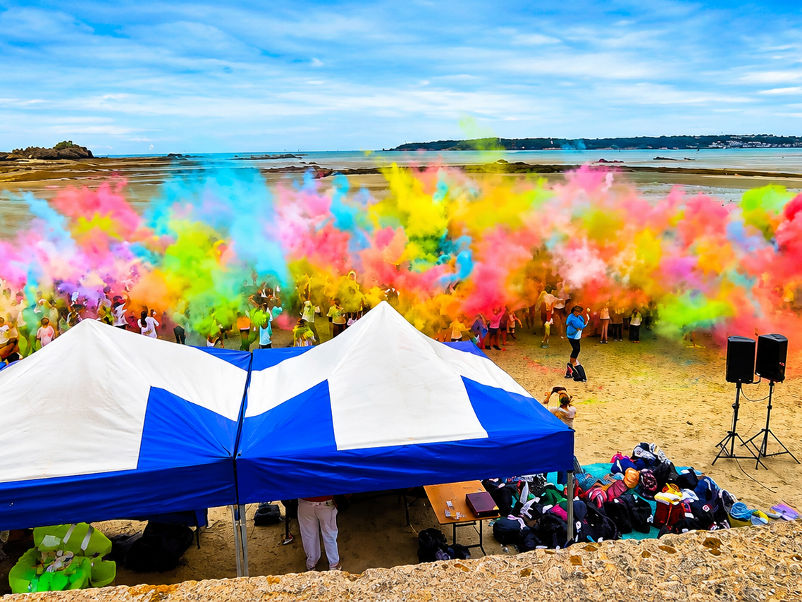 Participants throwing vibrant colour powder during a beach colour run fundraiser at West Park Beach, Jersey, raising £40,000 for Family Nursing & Home Care.