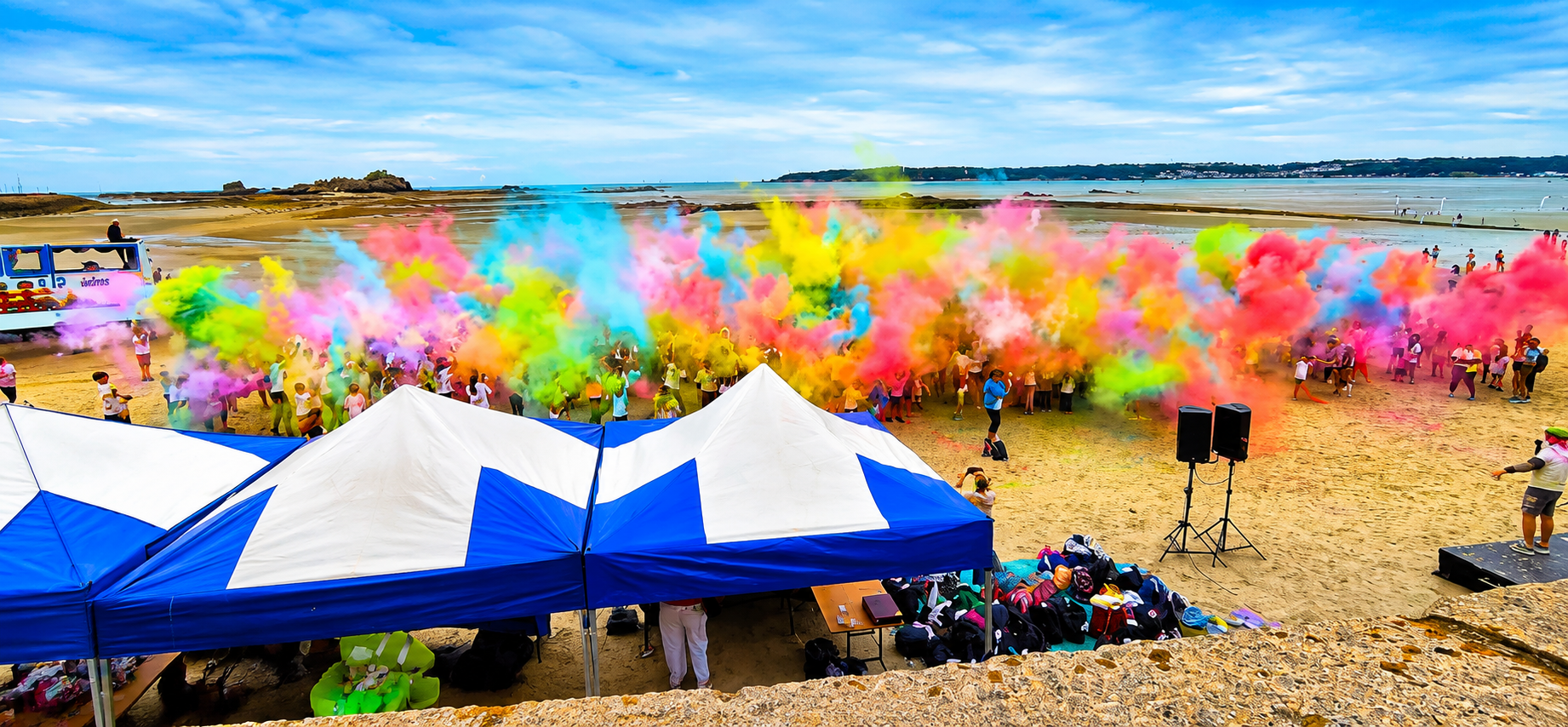 Participants throwing vibrant colour powder during a beach colour run fundraiser at West Park Beach, Jersey, raising £40,000 for Family Nursing & Home Care.