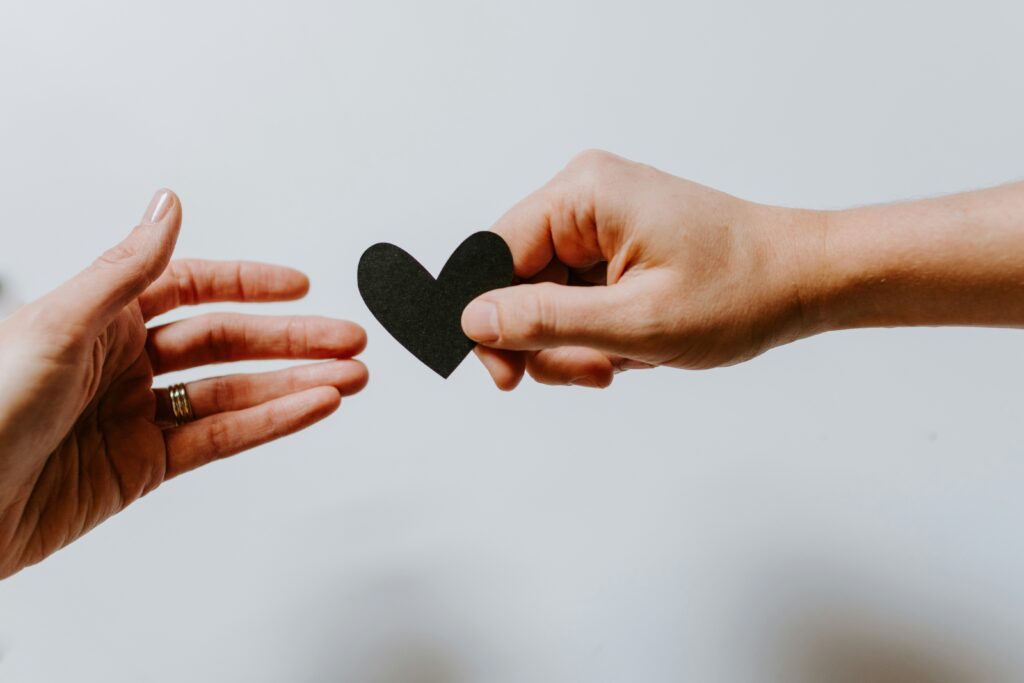 Hands exchanging a heart to represent donations and Gift Aid for school fundraising